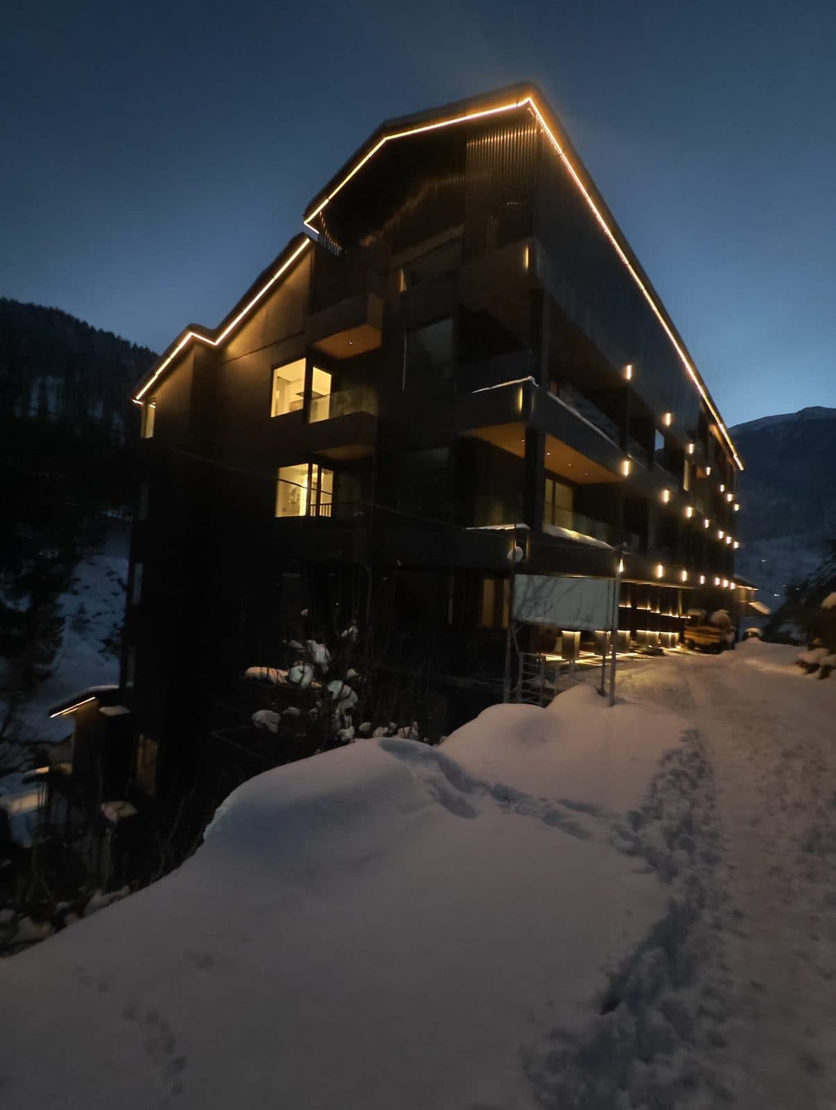 EKAM's forest-facing architecture, lit at dusk in the Himalayan snow